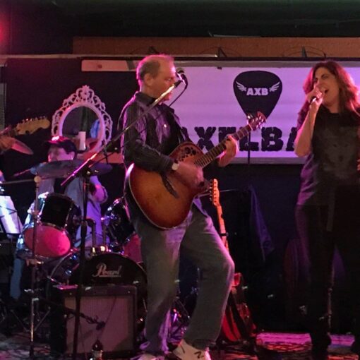 A man and woman singing on stage with other people.
